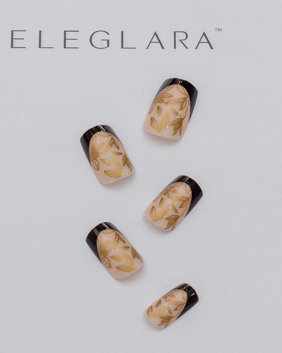 Five press-on nails with a nude base, gold botanical leaf patterns, and glossy black French tips, arranged on a white background with the Eglara Beauty logo.
